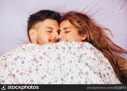 Young smiling heterosexual couple lying down together on the bed