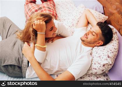 Young smiling heterosexual couple lying down together on the bed