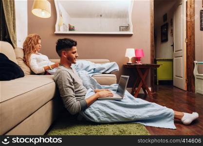 Young smiling heterosexual couple together on sofa using a laptop