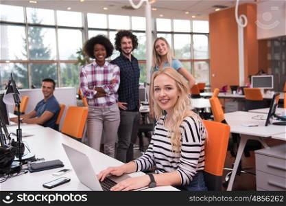 young smiling informal businesswoman working in the office with colleagues in the background