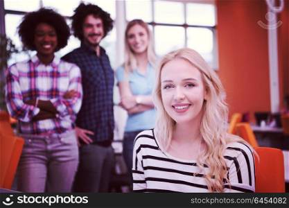 young smiling informal businesswoman working in the office with colleagues in the background