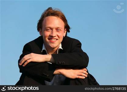 young smiling man against sky in suit