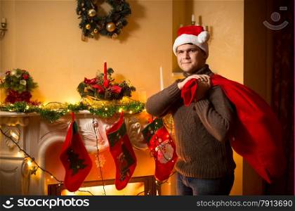 Young smiling man carrying big Santa bag with gifts on Christmas eve