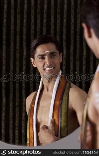 Young smiling man looking at self in mirror