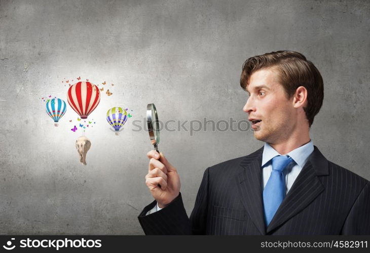 Young smiling man looking in magnifying glass. Man with magnifier