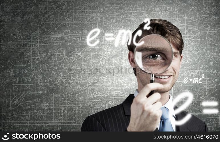 Young smiling man looking in magnifying glass. Man with magnifier