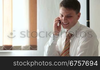 young smiling man talking on a cell phone in the living room