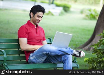Young smiling man using laptop in lawn
