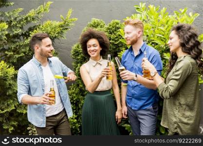 Young smiling people stand outside and toast with cider in the hands outdoor