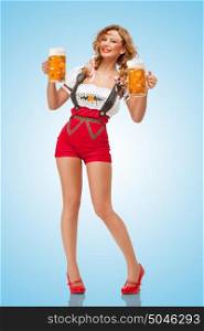 Young smiling sexy Swiss woman wearing red jumper shorts with suspenders in a form of a traditional dirndl, holding two beer mugs on blue background.