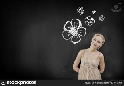 Young smiling student or teacher at the blackboard. Pretty woman at blackboard