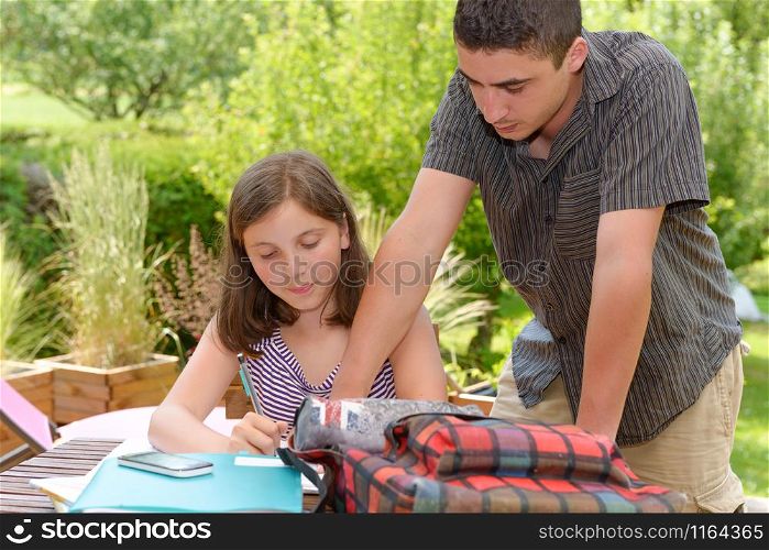 young smiling teenager girl doing her homework with her brother