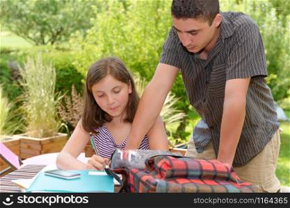 young smiling teenager girl doing her homework with her brother