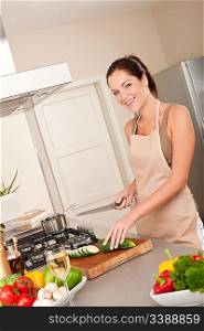 Young smiling woman cutting zucchini in the kitchen