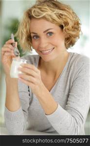 young smiling woman eating yogurt