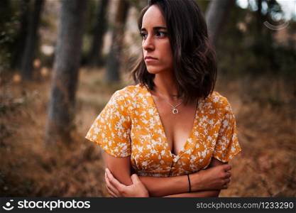 Young smiling woman embraced herself wearing dress in the forest