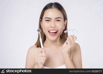 Young smiling woman holding invisalign braces in studio, dental healthcare and Orthodontic concept