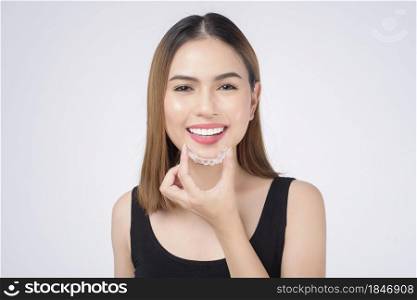 Young smiling woman holding invisalign braces in studio, dental healthcare and Orthodontic concept