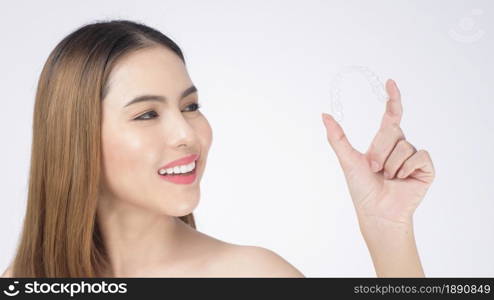 Young smiling woman holding invisalign braces in studio, dental healthcare and Orthodontic concept