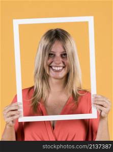 young smiling woman holding white border frame front her face