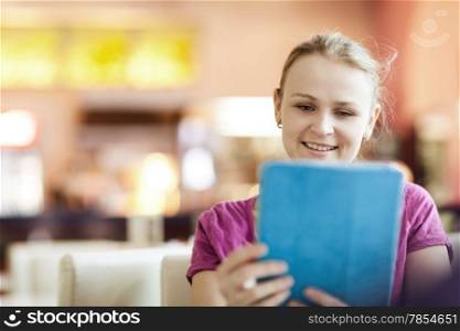 Young smiling woman in cafeteria using tablet computer