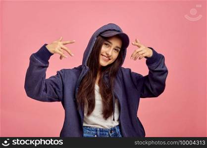 Young smiling woman in hoodie, pink background, emotion. Face expression, female person looking on camera in studio, emotional concept, feelings. Young smiling woman in hoodie, pink background