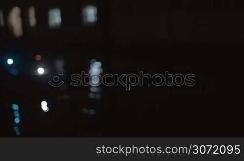 Young smiling woman in mask making selfie with smart phone by the window against water background at night. Atmosphere of Venetian carnival