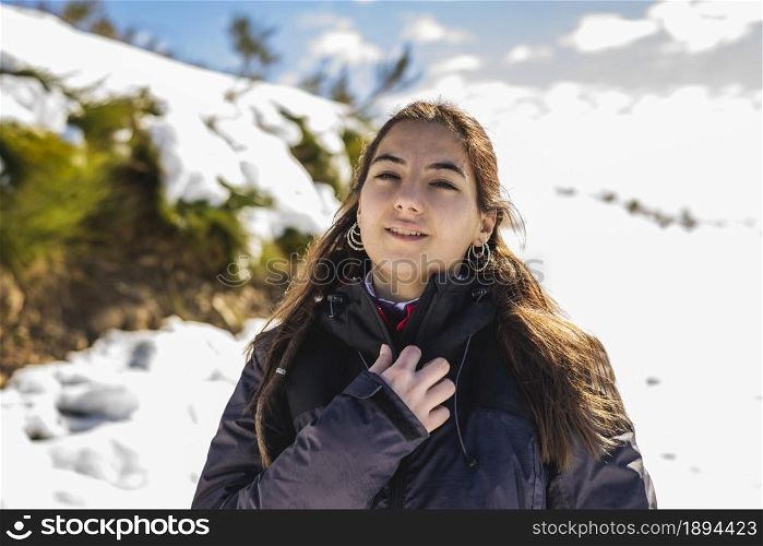 Young smiling woman in snowy mountains at sunset in winter.