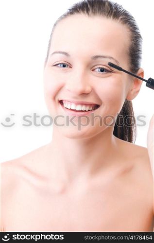 young smiling woman is applying mascara on her face and looking at camera, isolated on white