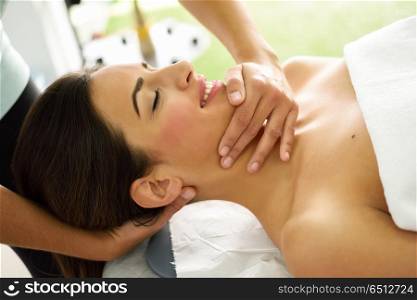 Young smiling woman receiving a head massage in a spa center.. Young caucasian smiling woman receiving a head massage in a spa center with eyes closed. Female patient is receiving treatment by professional therapist.