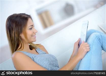 young smiling woman sitting on sofa with tablet