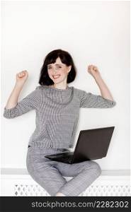 Young smiling woman with laptop making victory sign isolated over white background. Young smiling woman with laptop making victory sign isolated over white background.