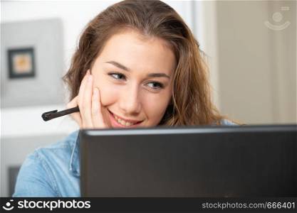young smiling woman with long hair is using a laptop