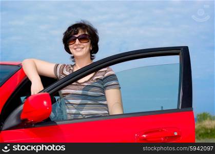 Young smiling woman with red car
