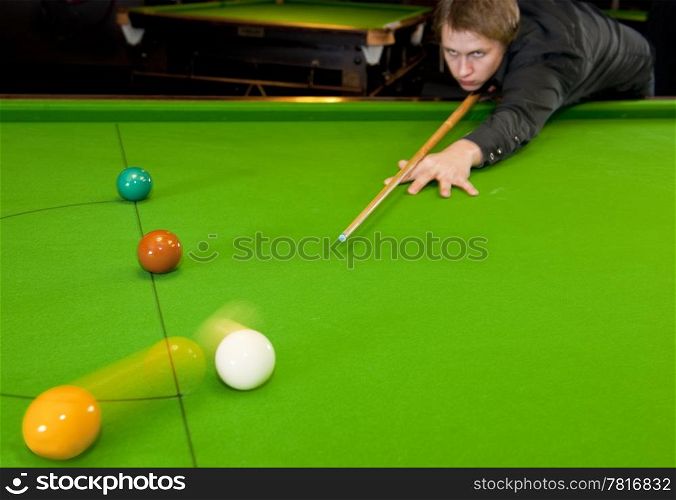 Young snooker playing shooting the cue ball (selective focus on cue tip)