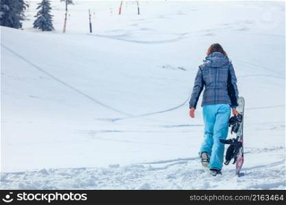 young snowboarder girl in winter clothes with snowboard in her hands. Snowboarder girl