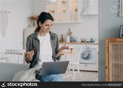 Young spanish woman has conversation on computer. Businesswoman has corporate internet group call. Girl staying home and sitting on sofa in living room. Online meeting on quarantine.. Young spanish woman has conversation on computer. Businesswoman has corporate group call at home.