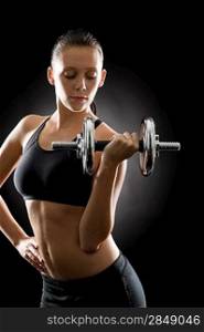 Young sport woman holding adjustable dumbbell on black background