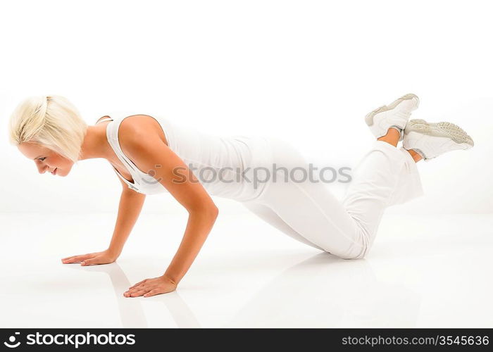 Young sportive woman doing pushups on white background