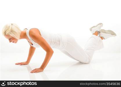 Young sportive woman doing pushups on white background
