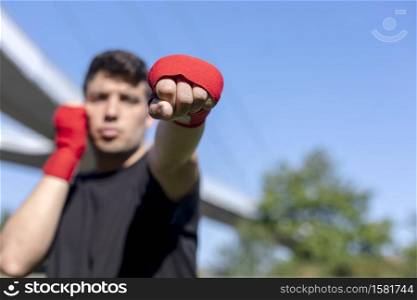 Young sports fitness man outdoors in park make boxing exercises.