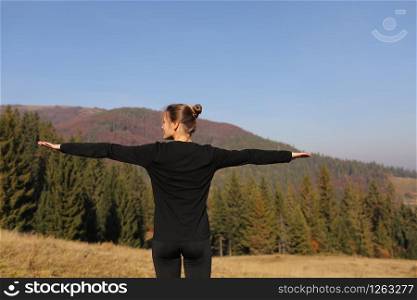 Young sports woman doing yoga exercise on the mountains and sky background in the autumn.. Young sports woman doing yoga exercise on the mountains and sky background in the autumn