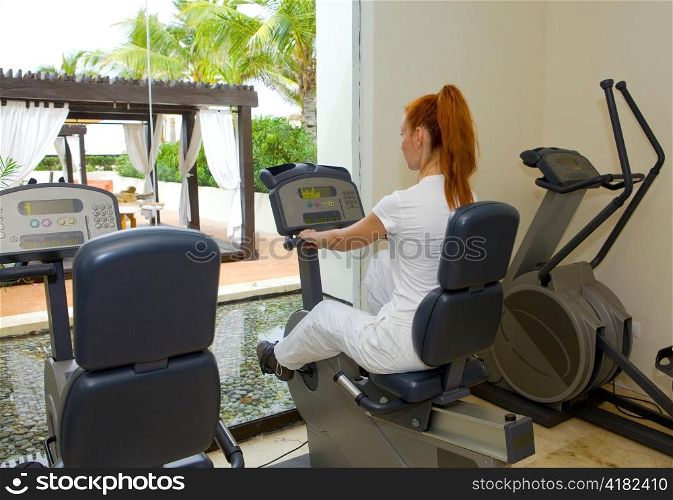 Young sports woman in sport center on velosimulator
