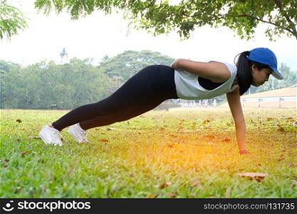 young sports woman plank exercise in garden