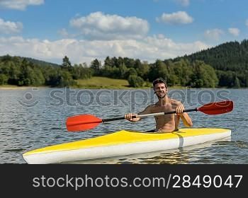 Young sportsman kayaking on sunny day on lake