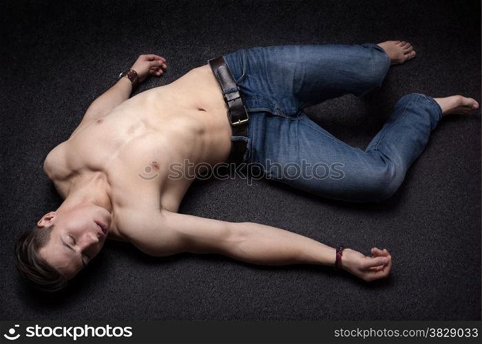 Young sportsman lying down unconsciously on apparent asphalt floor