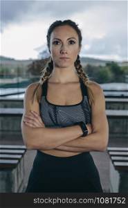 Young sportswoman posing arms crossed outdoors on a rainy day. Sportswoman posing arms crossed