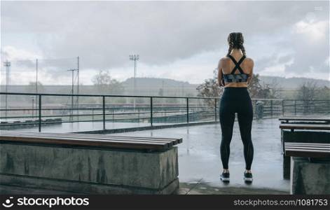Young sportswoman posing on her back watching the rain outdoors. Sportswoman posing backwards watching the rain
