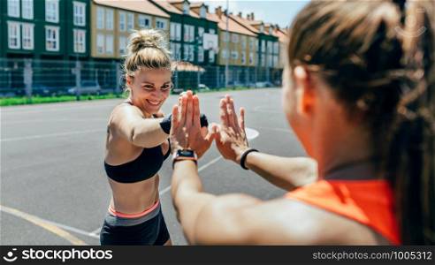 Young sportswoman training boxing with her trainer outside. Sportswoman training boxing with her trainer