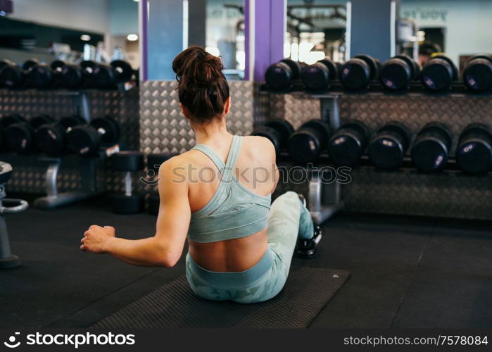 Young sportswoman wearing sportswear, on yoga mat doing situps in gym. Fitness woman doing abs crunches.. Sporty young female on yoga mat doing situps in gym.